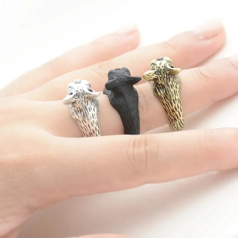 Back view of French Bulldog rings showing textured fur details in silver, black, and bronze finishes