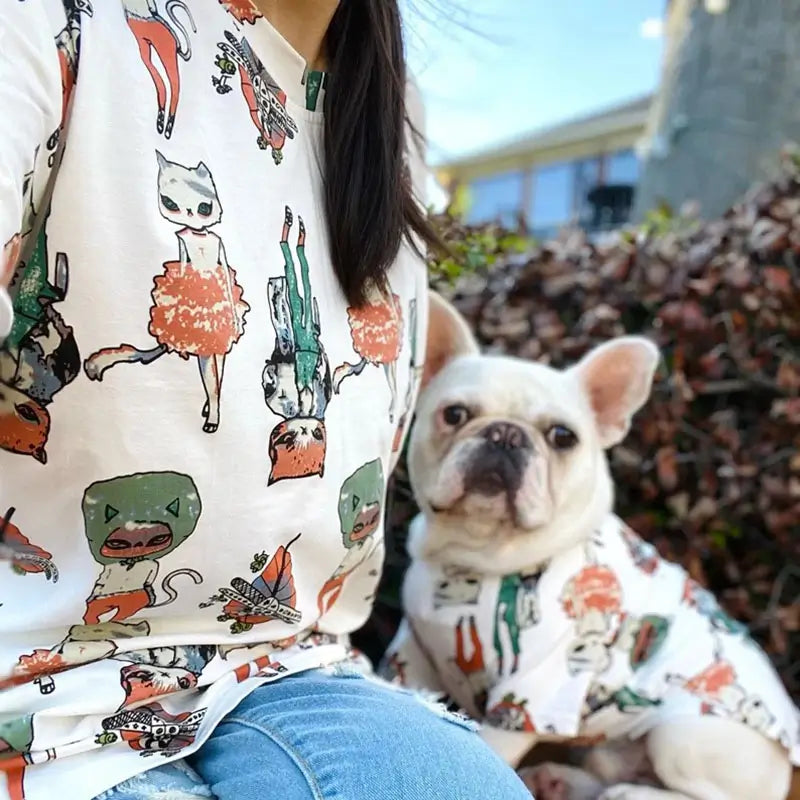 Matching family t-shirts for owner and French Bulldog with whimsical cartoon cat print, outdoor lifestyle photo
