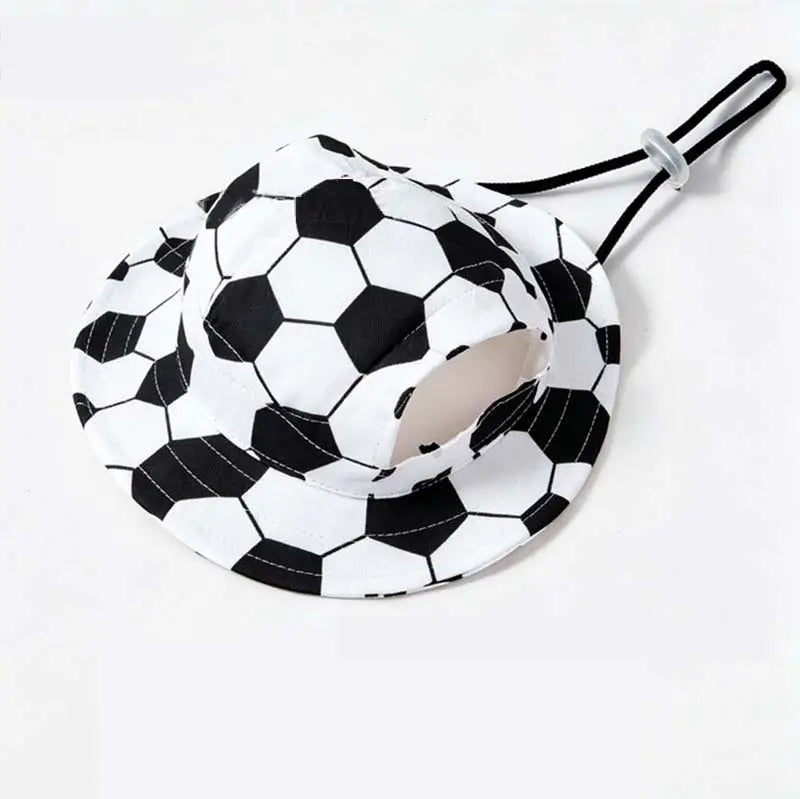 Black and white soccer ball patterned bucket hat for dogs, designed with ear holes and an adjustable chin strap, shown on a white background.