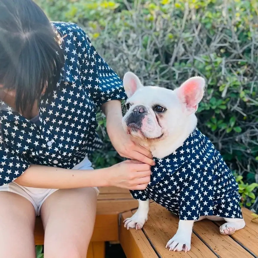 Matching navy star print shirt set for owner and French Bulldog, worn outdoors on a wooden bench, showing the dog shirt fit and coordinated design.
