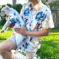 Matching watercolor floral print shirt set for male owner and French Bulldog, worn outdoors on a grassy lawn, highlighting the pet shirt fit and family matching style.