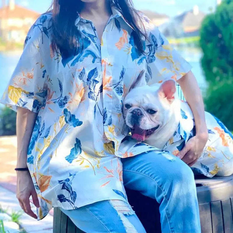 Matching watercolor floral print shirt set for female owner and French Bulldog, worn outdoors by a lake, showing the coordinated design and relaxed fit.