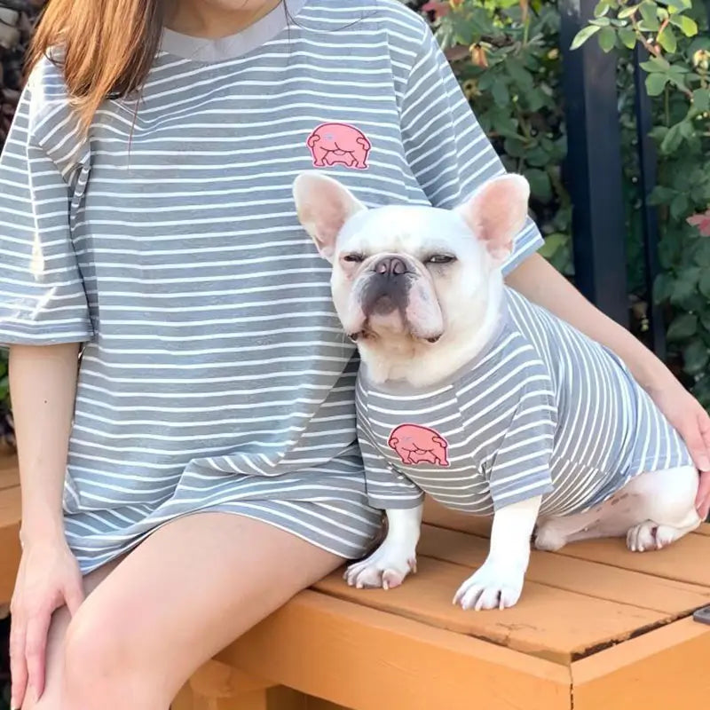 Full view of owner and white French Bulldog wearing matching grey stripe pig patch tees, casual family matching pet clothes for daily wear